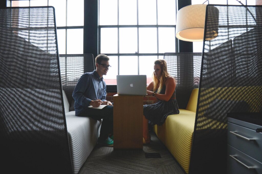Two colleagues discussing risk priorities at a laptop in a modern office setting.